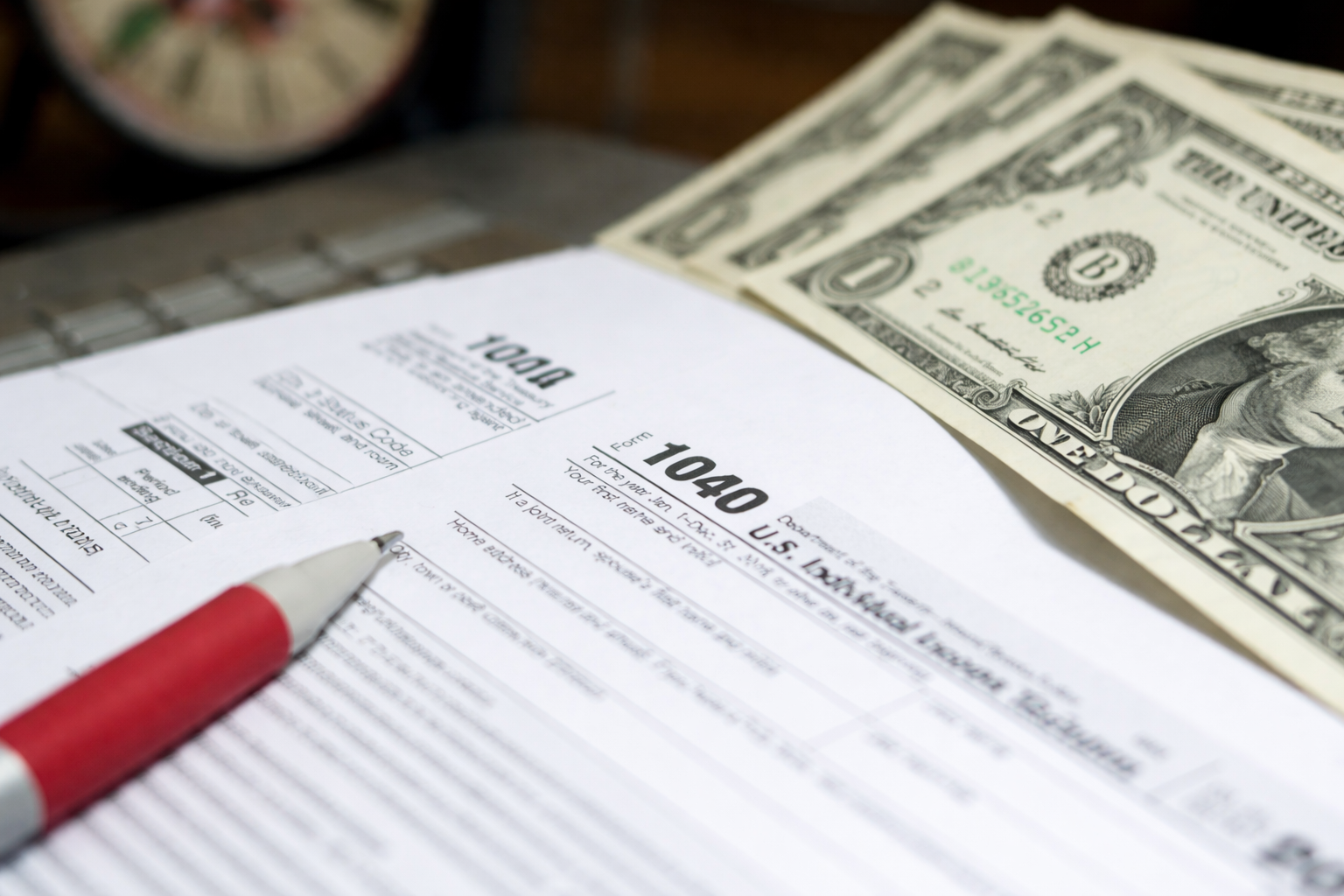 Employee stock options and taxes illustrated by IRS Form 1040 with cash and a pen, representing how stock option income can be taxable.