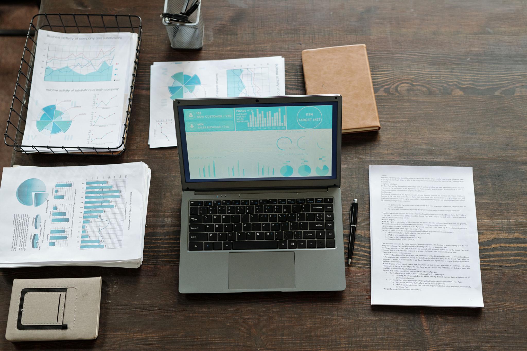 overhead view of laptop and financial reports showing business performance analysis