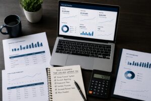 Laptop displaying financial dashboards with business reports, KPI metrics, cash flow analysis, and planning documents.